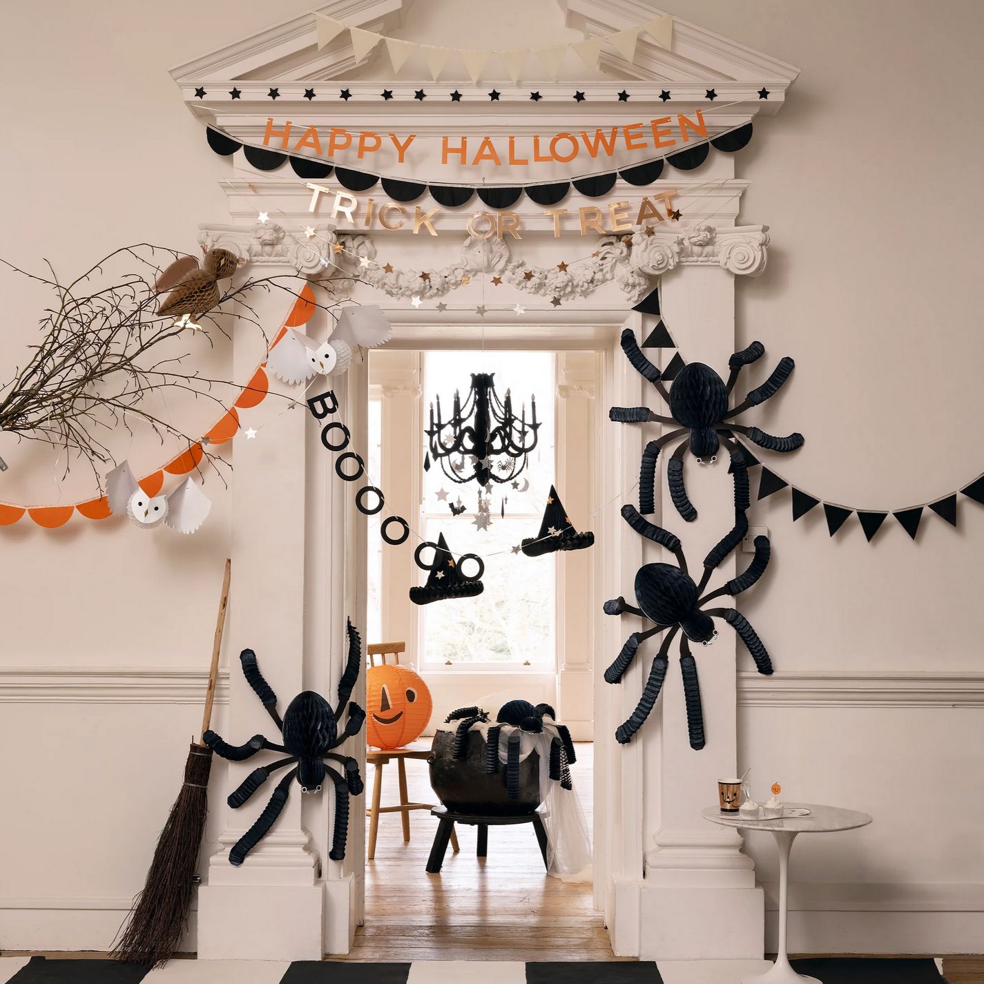 Halloween decorations including spiders, a broom, and 'Happy Halloween' banner in a room.