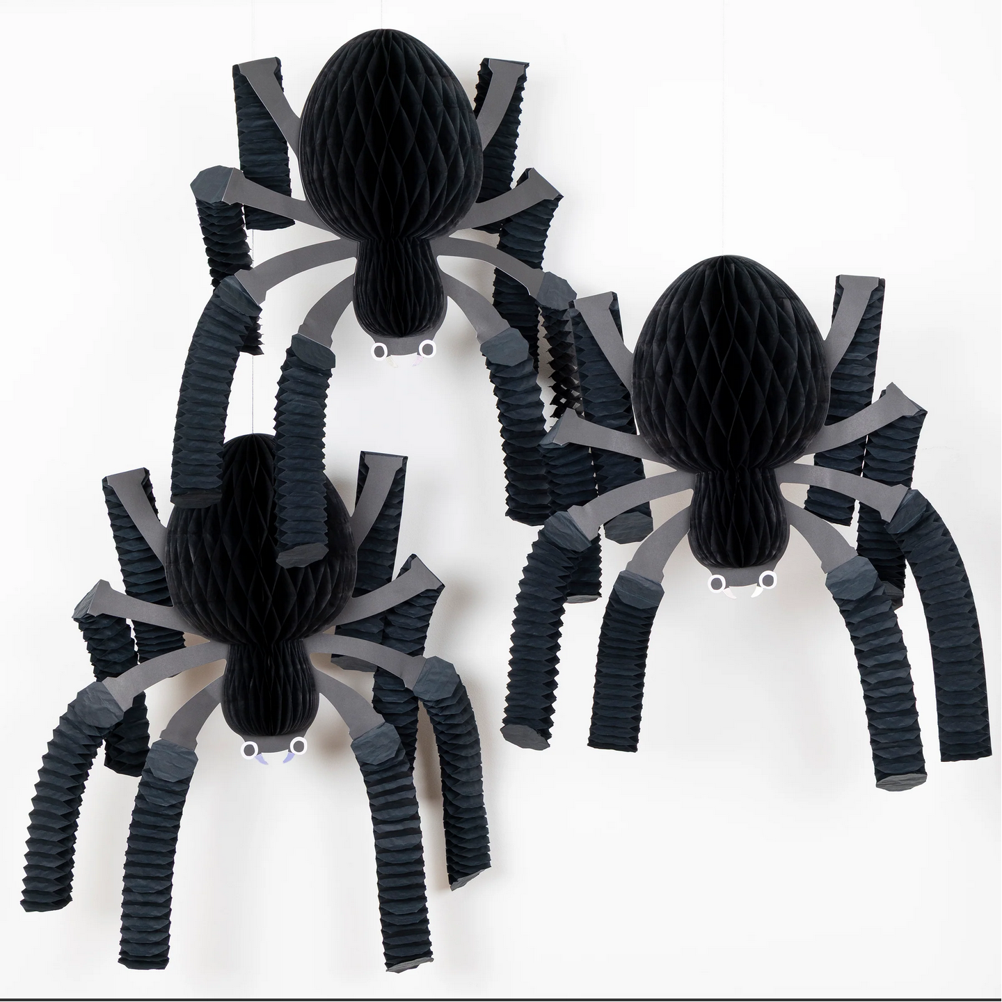 Three black spider decorations with gray legs on a white background