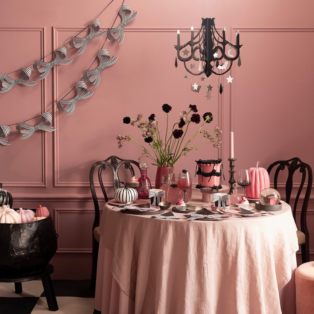 Decorative table setting with Halloween-themed decor in a room with pink walls.