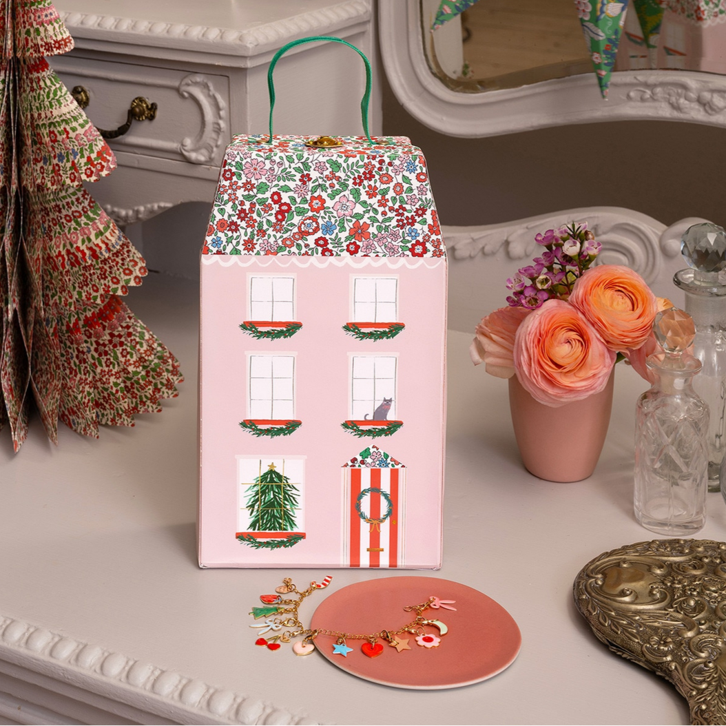 Decorative house-shaped box with floral design on a table with flowers and other decorative items.