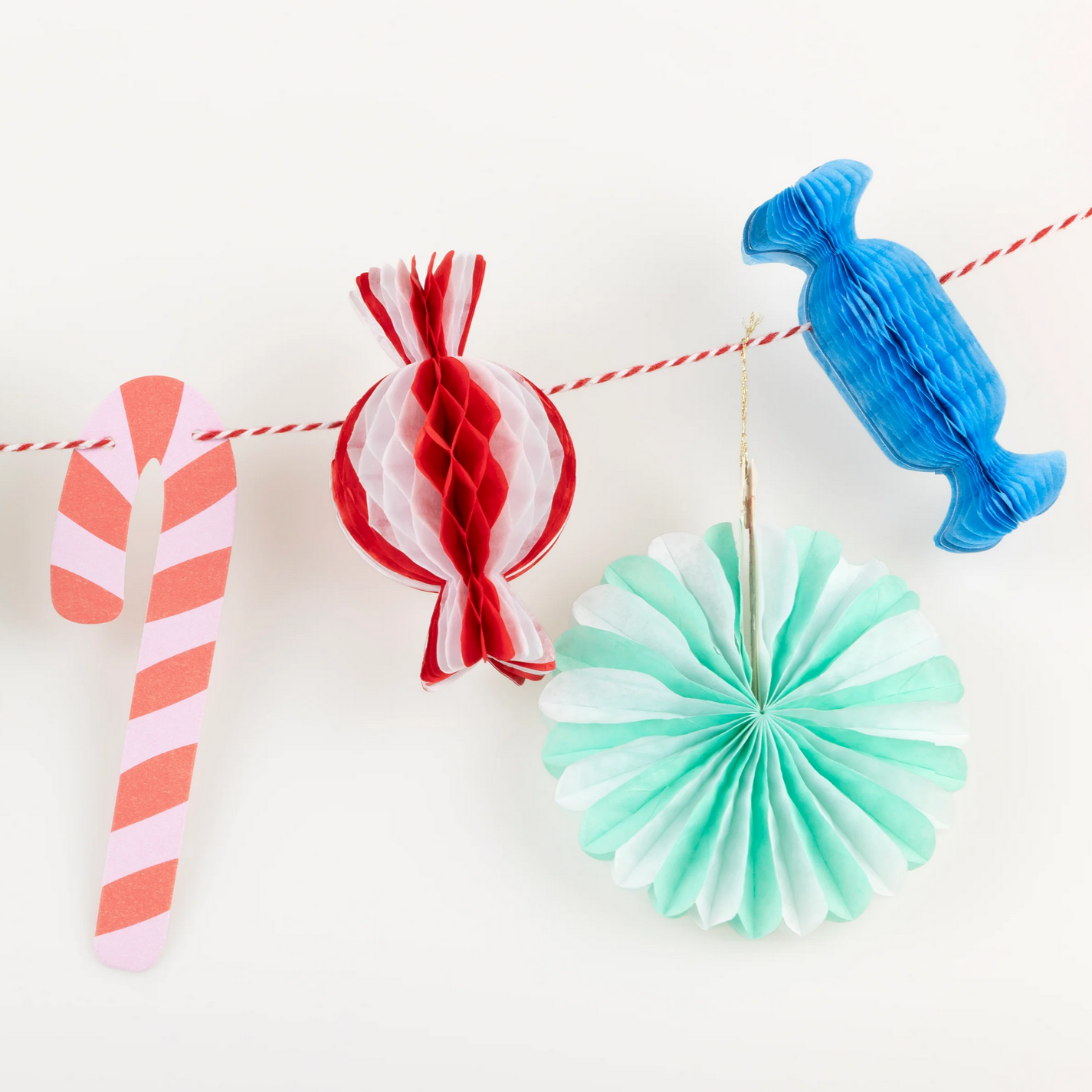 Decorative paper candy decorations on a string against a white background