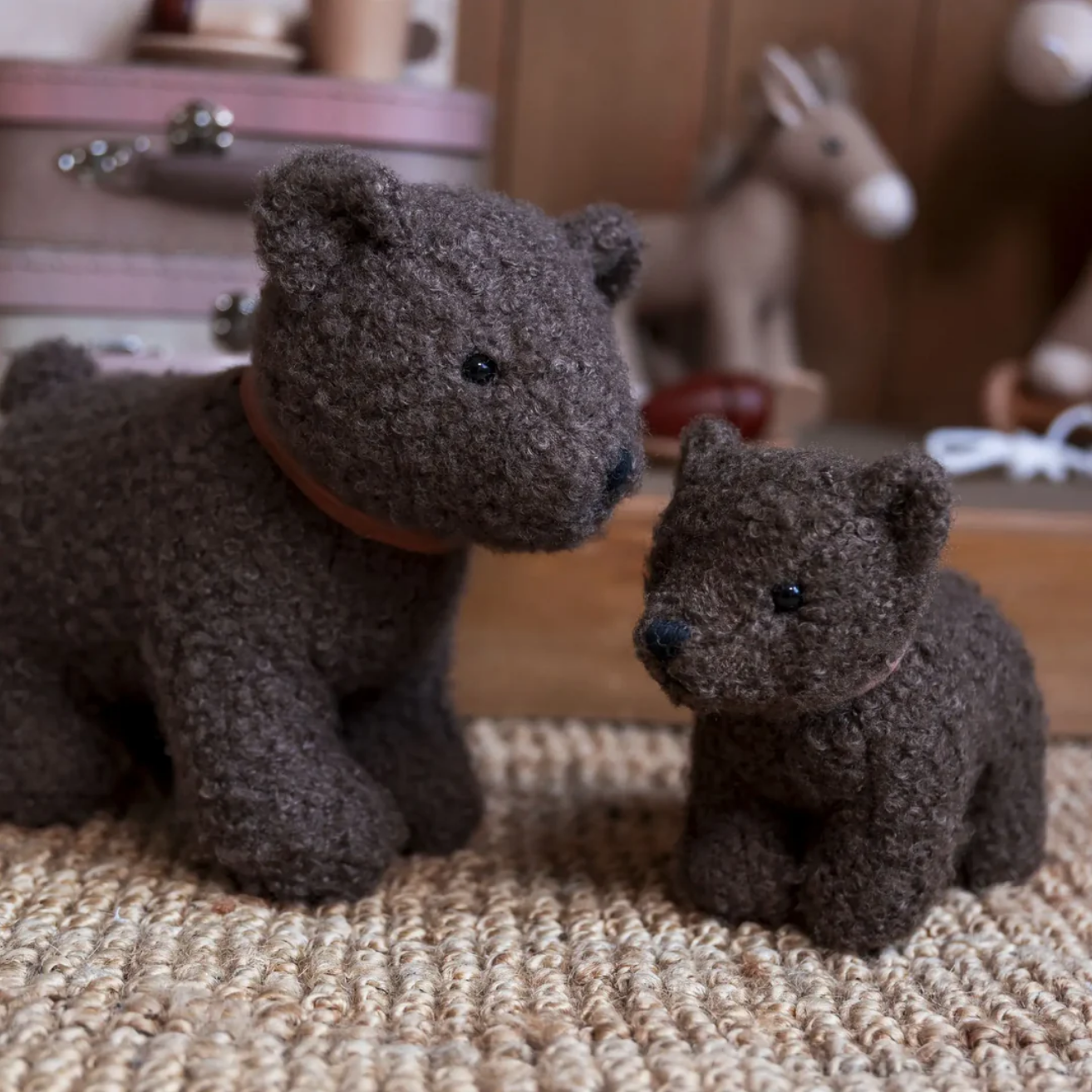 Two brown teddy bears sitting on a textured surface with a blurred background