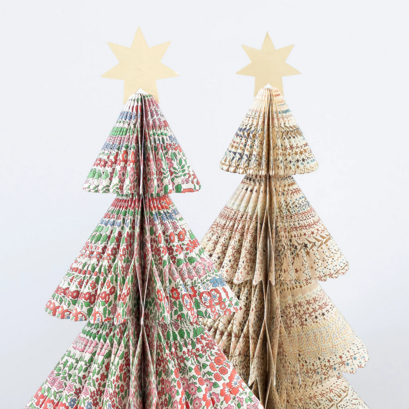 Two decorative paper trees with star toppers on a light gray background