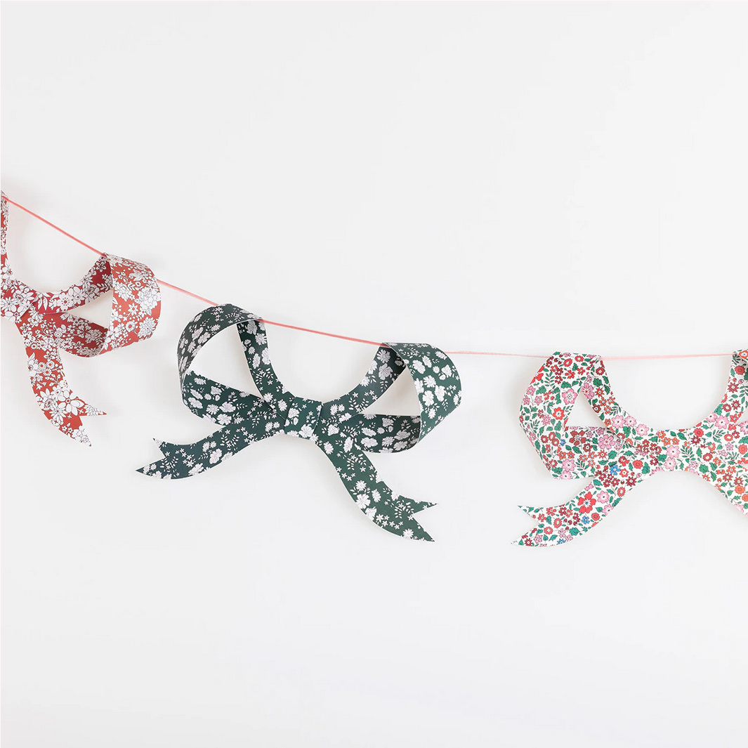 Decorative paper bows with floral patterns on a string against a white background