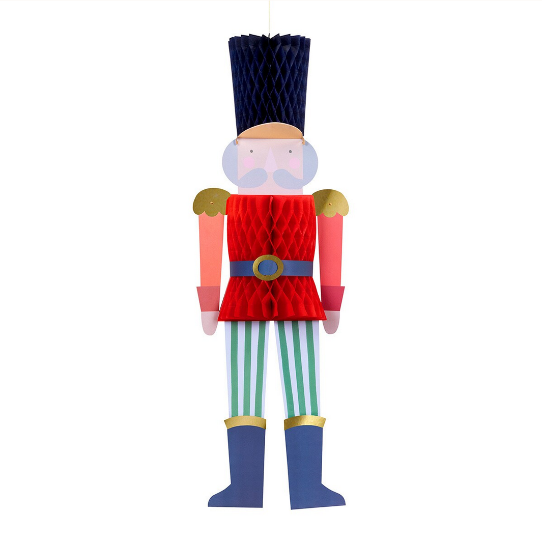 Decorative nutcracker figure with red outfit, blue boots, and striped pants on a white background