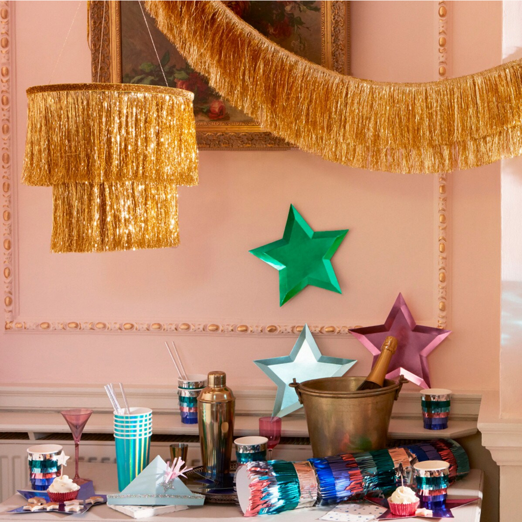 Decorative setup with colorful star-shaped balloons, a gold bucket, and festive decor on a table.