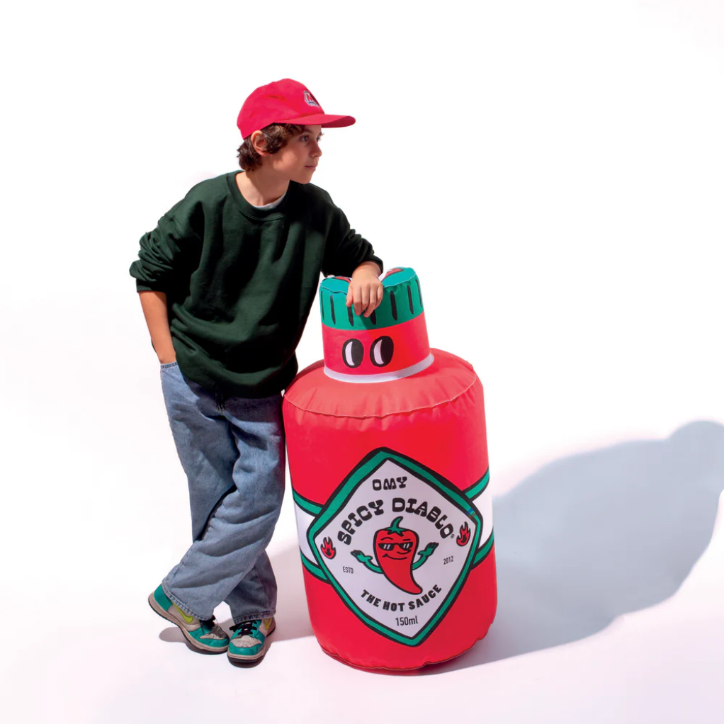 Child with a large inflatable spicy sauce container on a white background