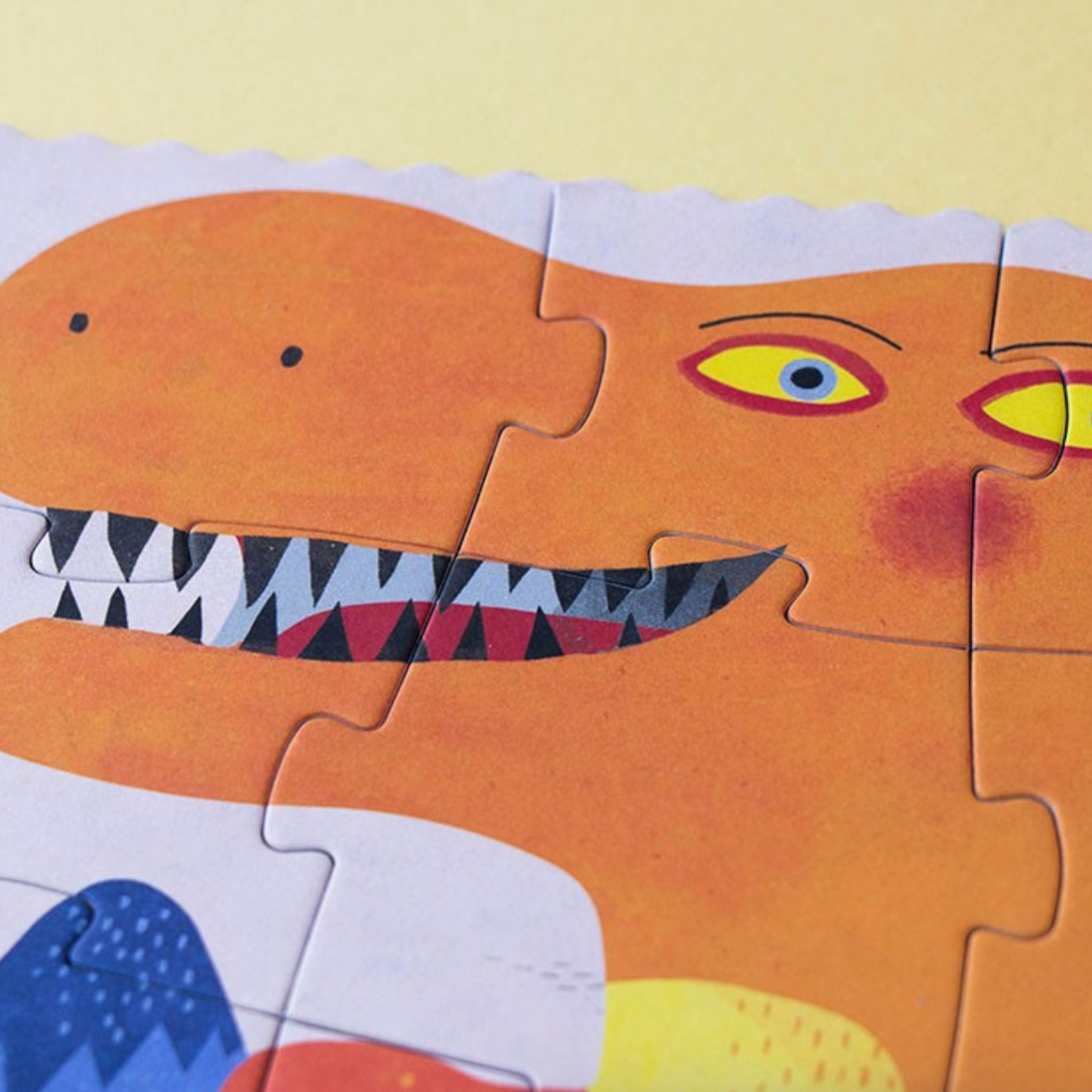 Children's dinosaur puzzle with missing pieces on a light yellow background