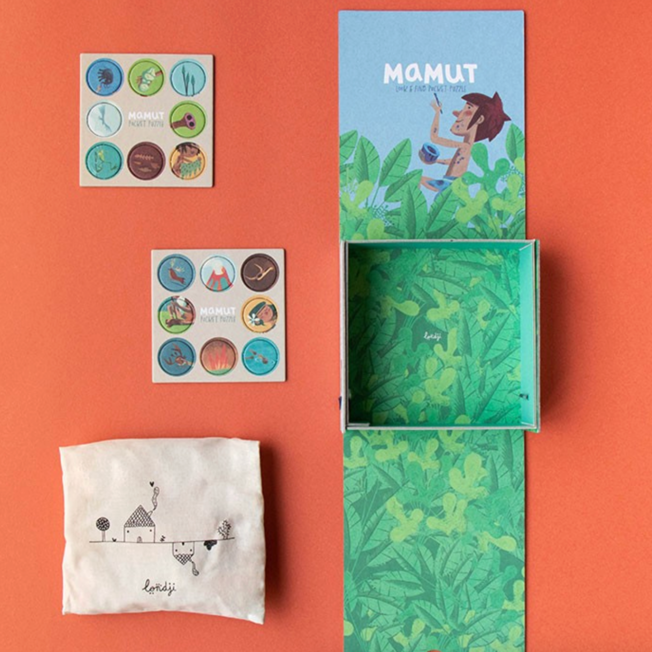Product packaging with a green box, stickers, and a cloth on an orange background