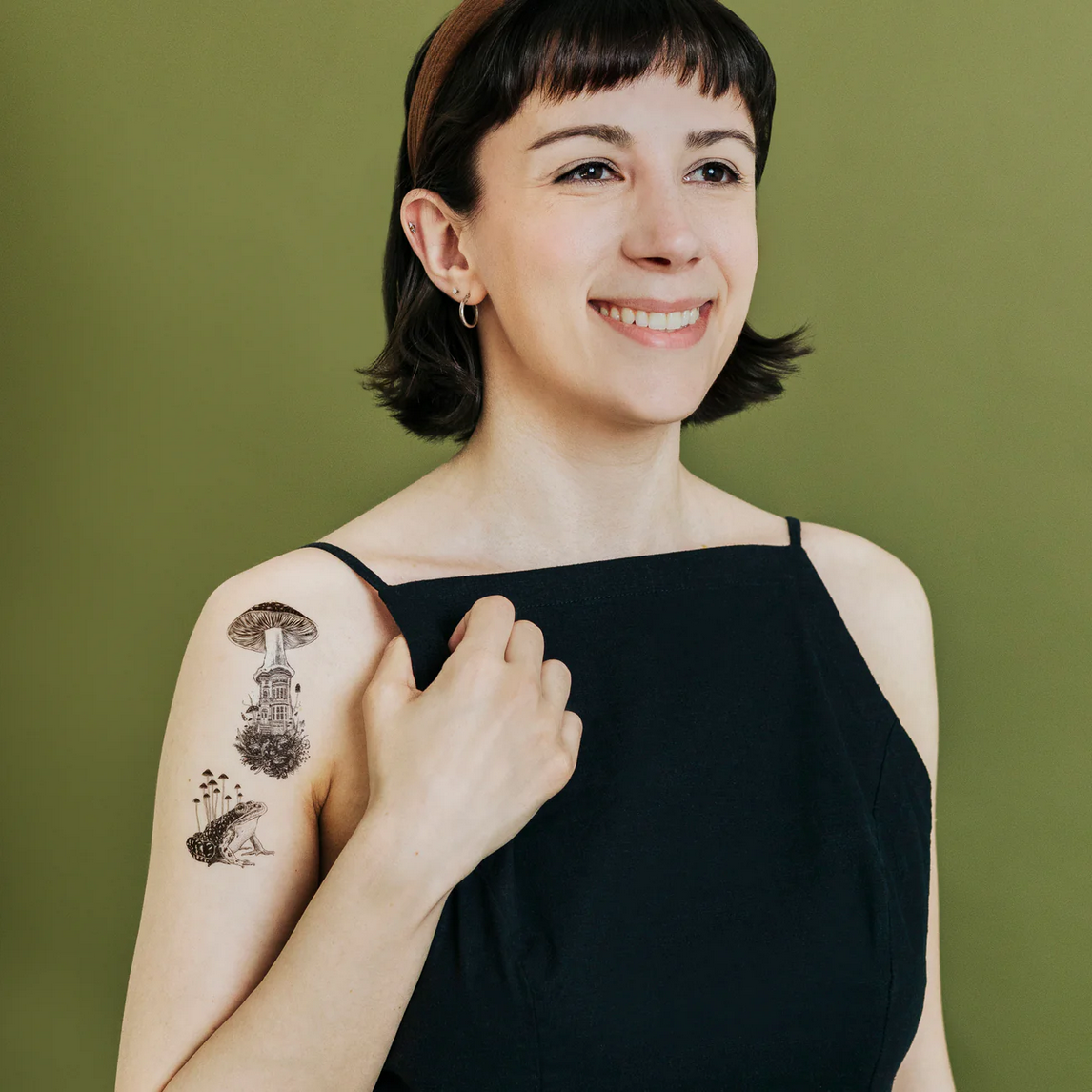 Woman with a tattoo on her arm against a green background