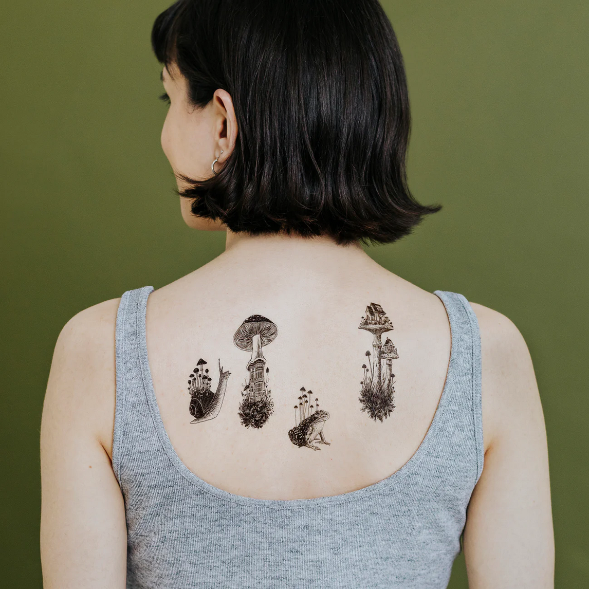 Person with mushroom tattoos on their back against a green background