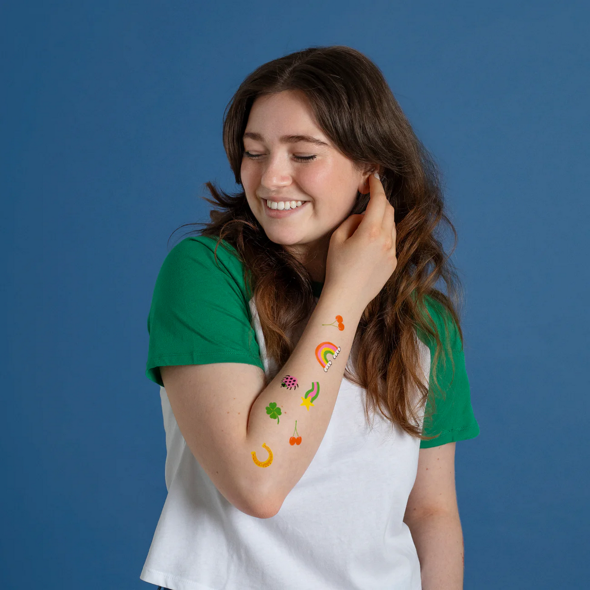 Woman with colorful temporary tattoos on her arm against a blue background