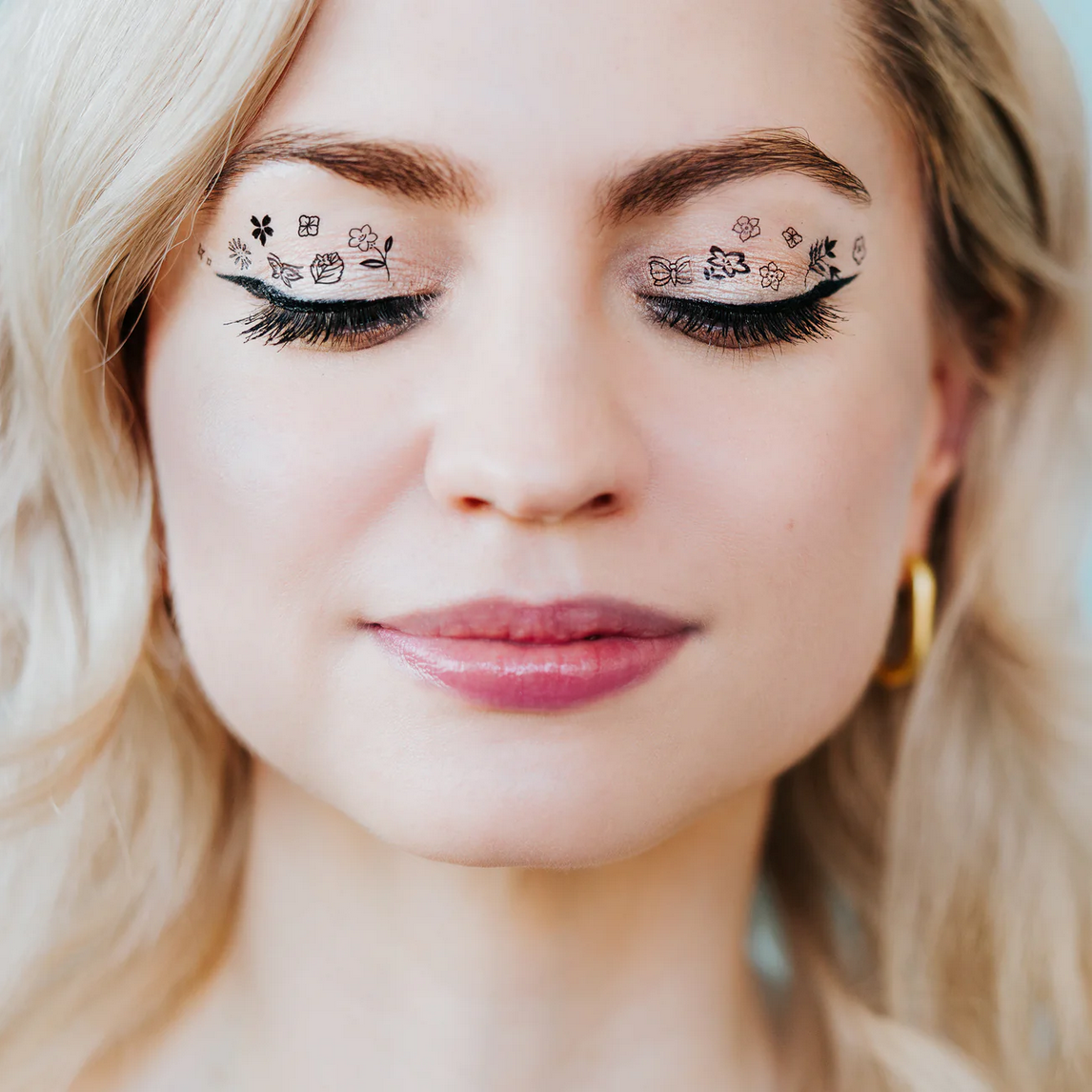 Close-up of a woman's face with decorative eye makeup.