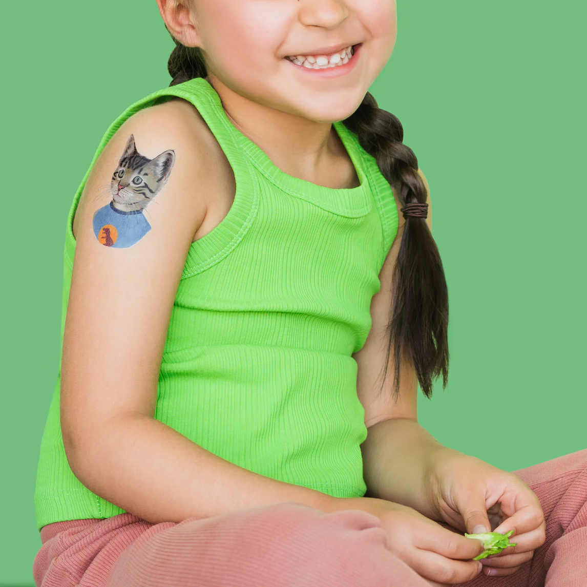 Girl with a temporary tattoo of a cat on her arm against a green background