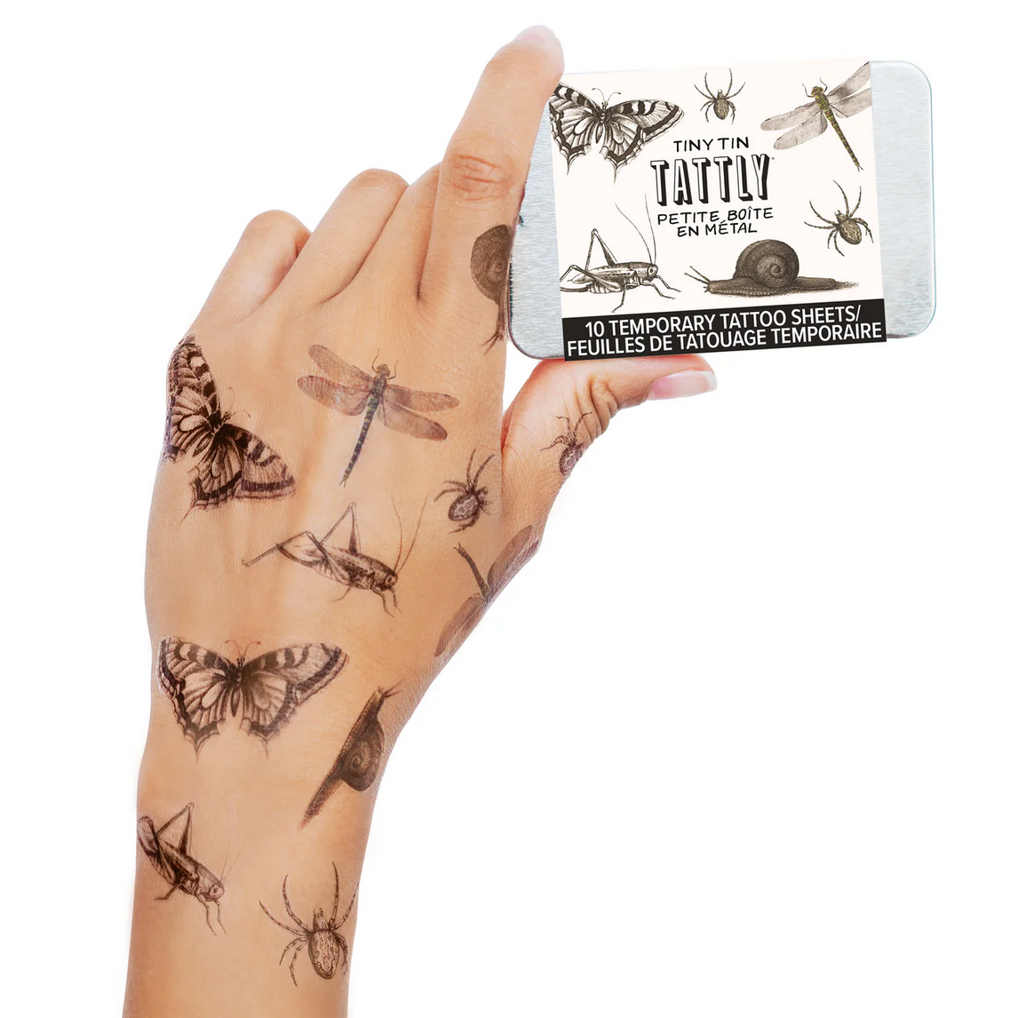 Hand with temporary tattoos and Tattly packaging on a white background