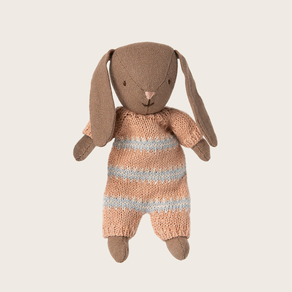 Knitted toy rabbit with a striped sweater on a light beige background