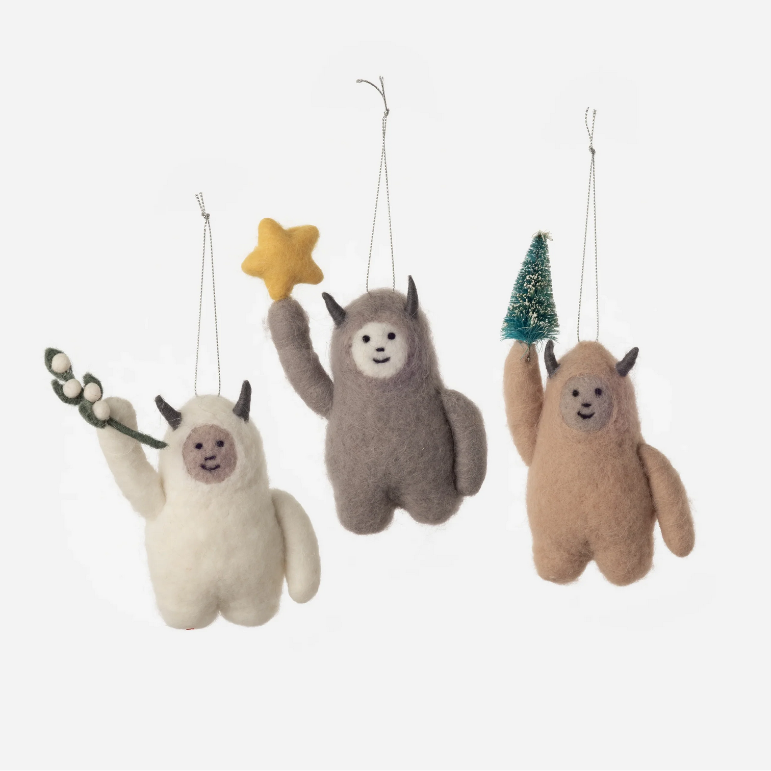 Three plush ornaments shaped like characters holding a star, branch, and small tree on a white background