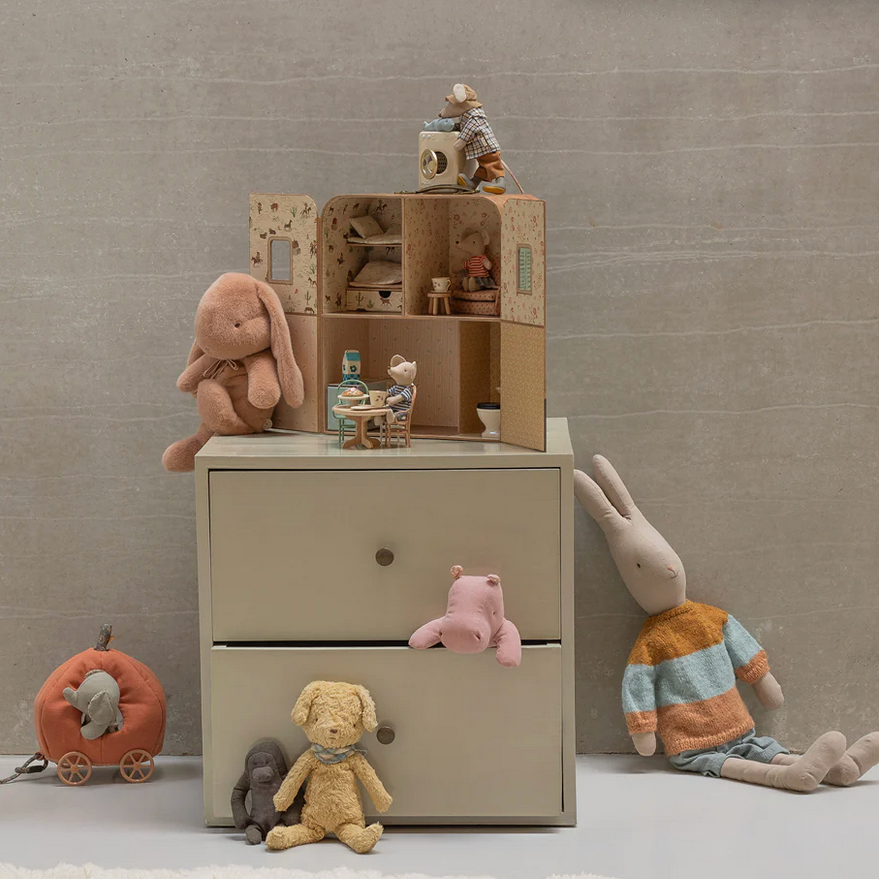 Children's room with a dresser, toys, and decorative items on a neutral background