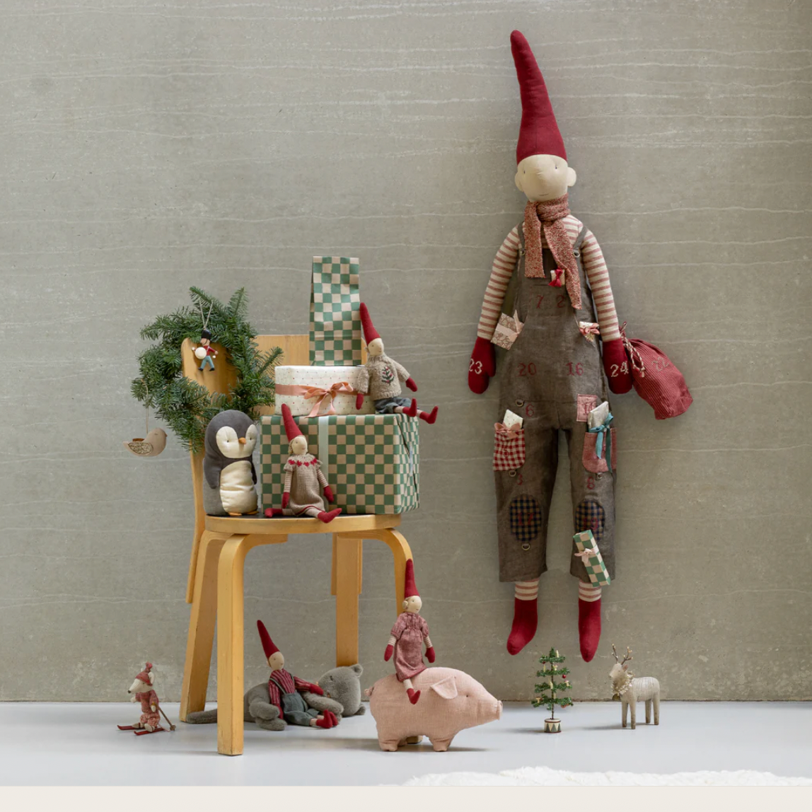 Decorative scene with gnomes and a small chair against a neutral wall.