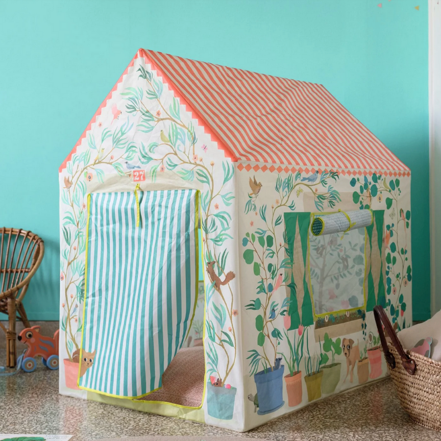 A colorful children's play tent with a floral and striped pattern set up indoors, next to a toy car and a wicker basket.