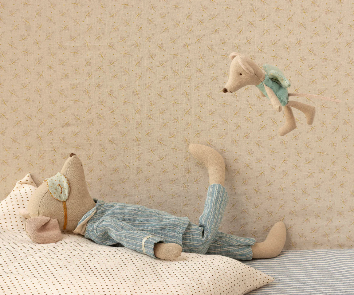 Stuffed animal toy hanging from a bed with a patterned wall in the background