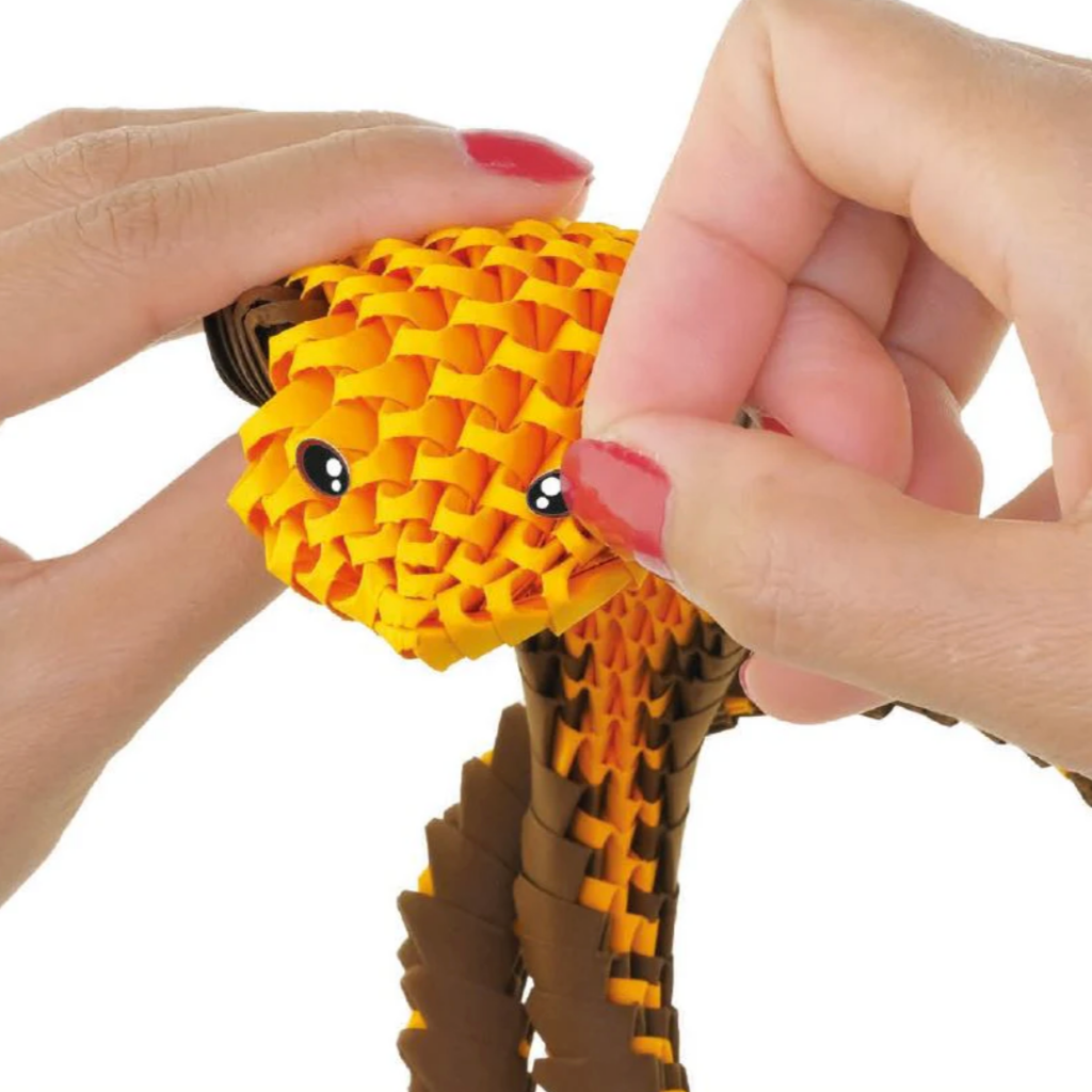 Hand holding a yellow and brown toy resembling a snake.