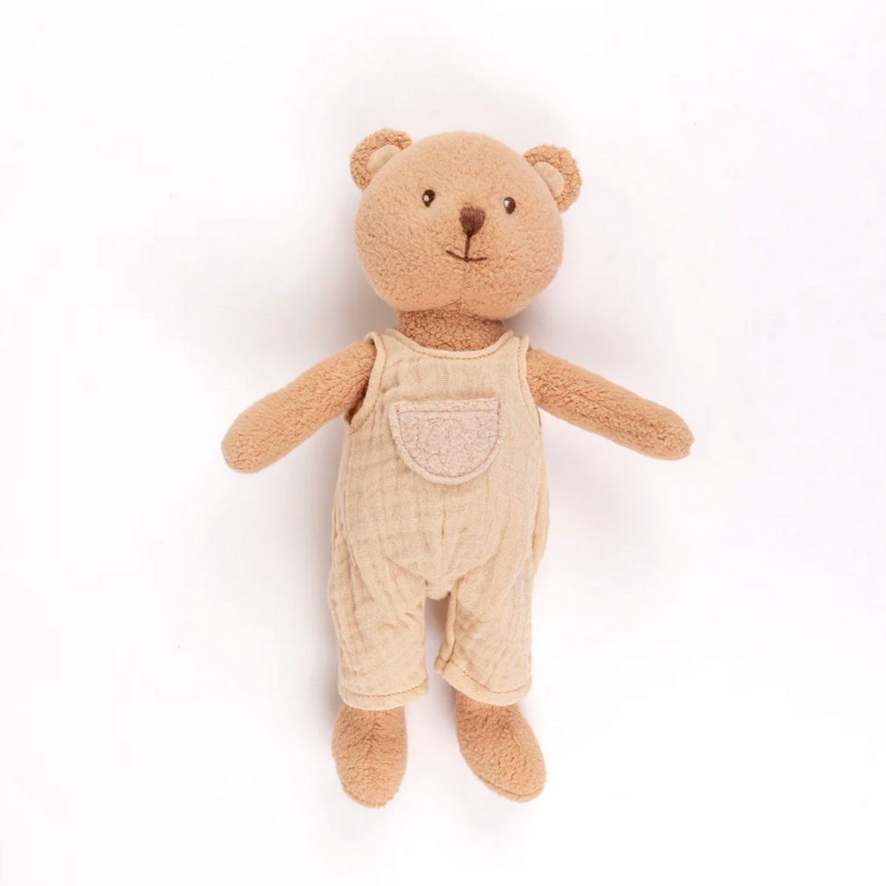 Stuffed teddy bear wearing beige overalls on a white background