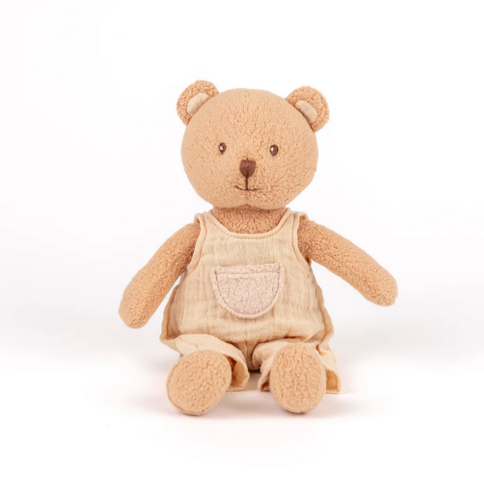 Beige teddy bear with a cream overalls on a white background