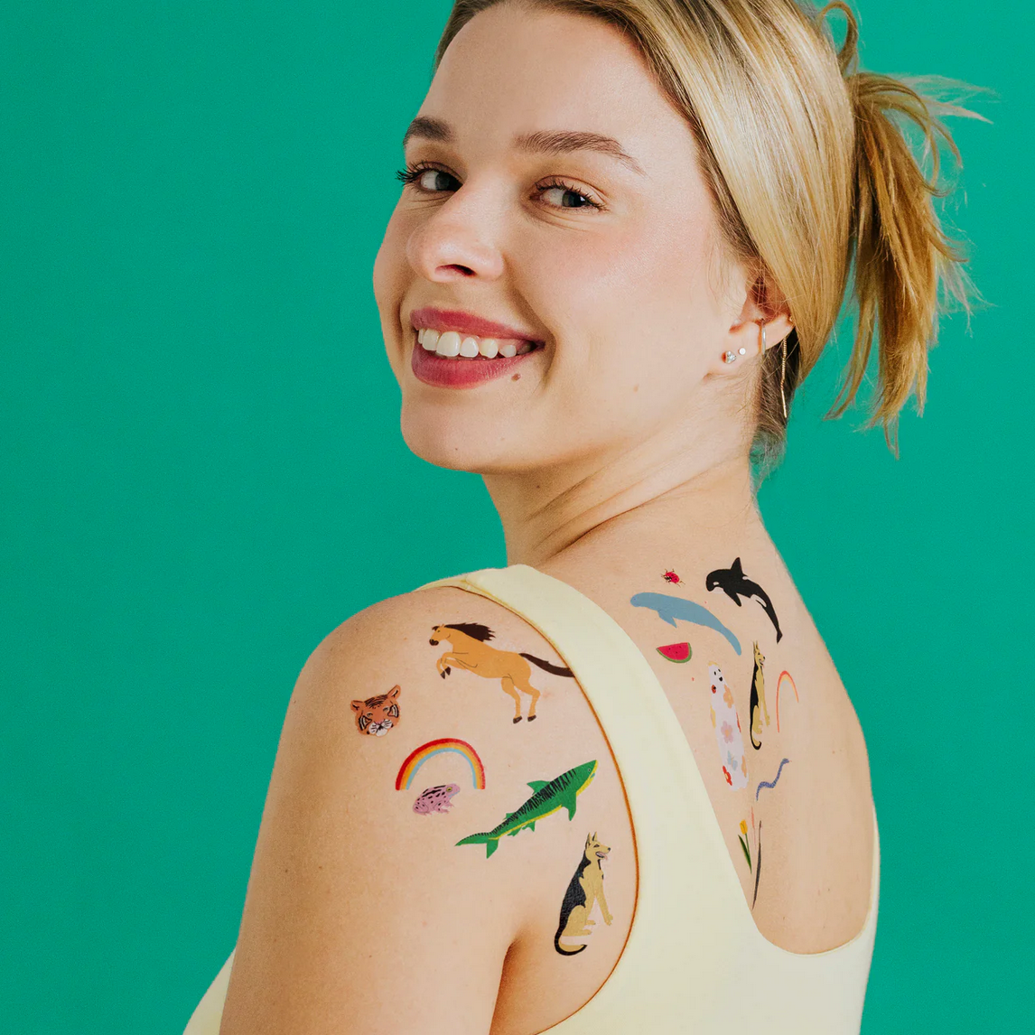 Woman with temporary tattoos of animals on her arm against a green background