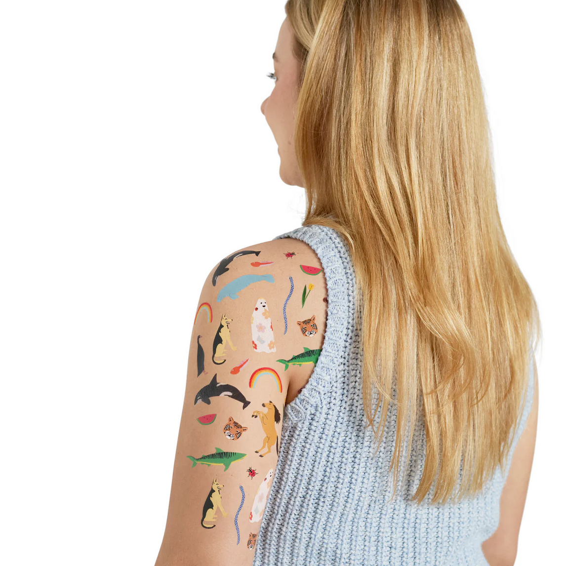 Woman with temporary tattoos of various animal designs on her arm against a white background