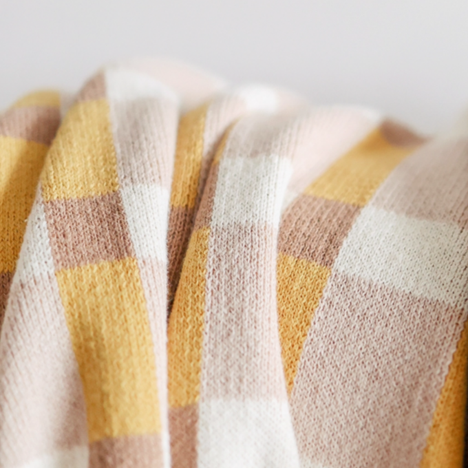 Two plaid blankets in different patterns on a light gray background