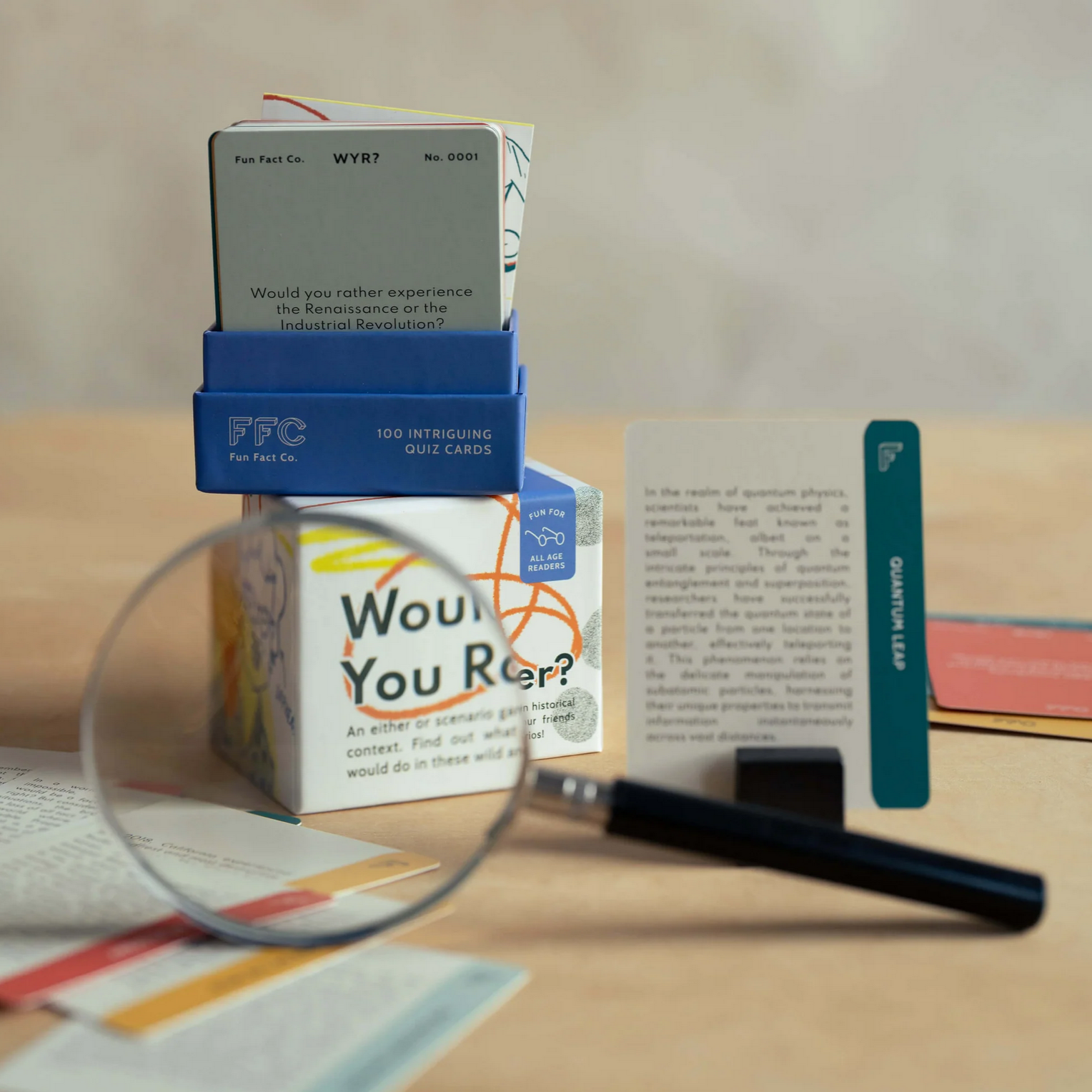 Magnifying glass over a box labeled 'Would You Rather?' with books and cards on a table.