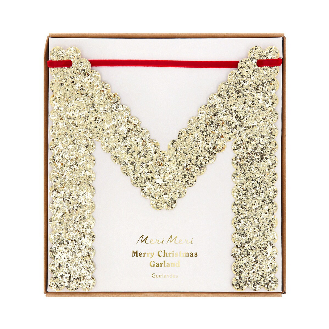 Gold glittery letter 'M' with a red ribbon on a white background