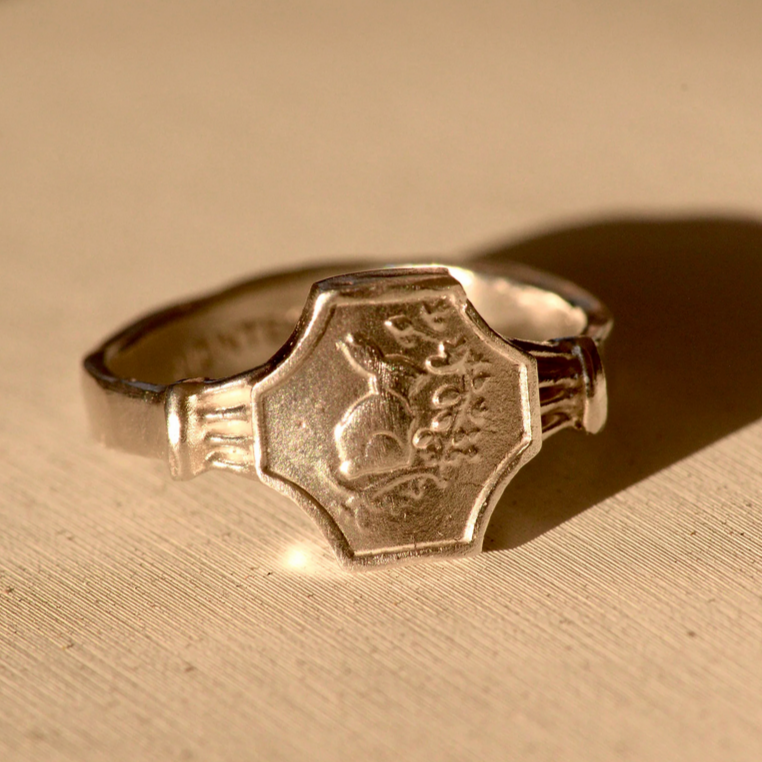 Silver ring with engraved design on a beige background