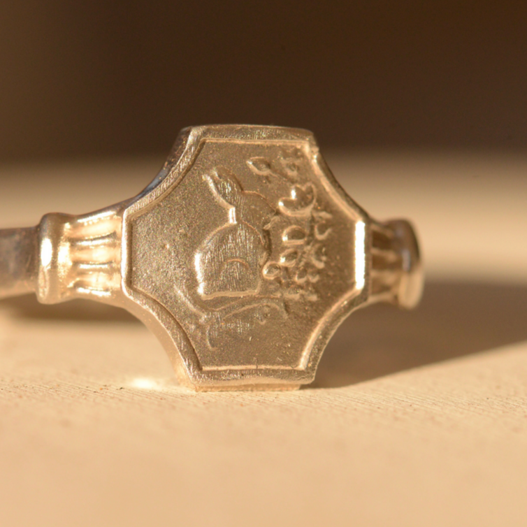 Silver ring with a distinctive design on a beige background