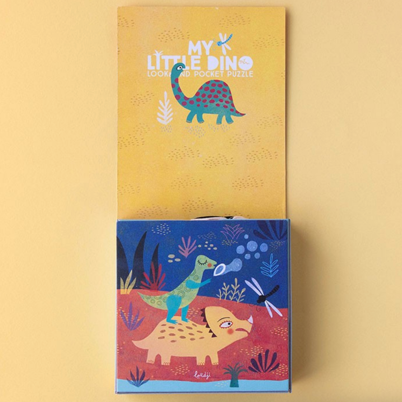 Two children's books with dinosaur illustrations on a beige background
