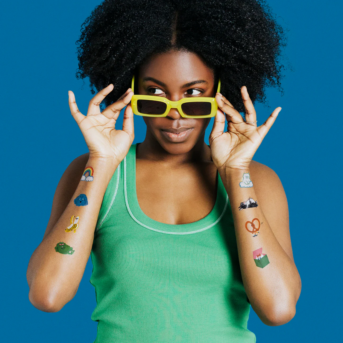 Woman wearing colorful temporary tattoos on her arms against a blue background
