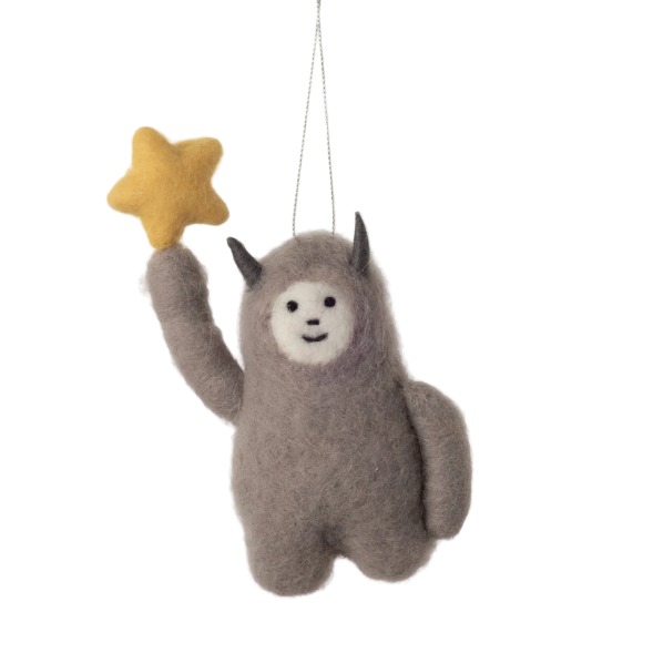 Felted animal ornament resembling a creature with horns holding a yellow star, hanging against a white background.