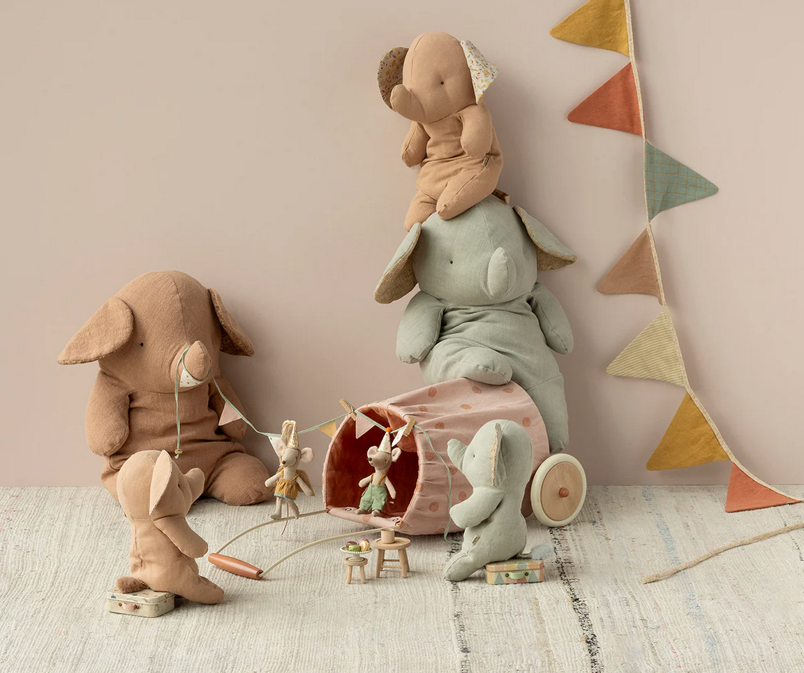 Children's toys including plush animals and a toy car on a light wooden floor with a neutral wall background.