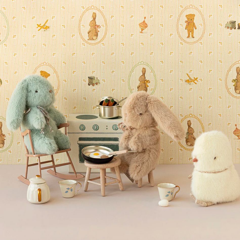 Children's play area with stuffed animals and toys against a decorative wall.