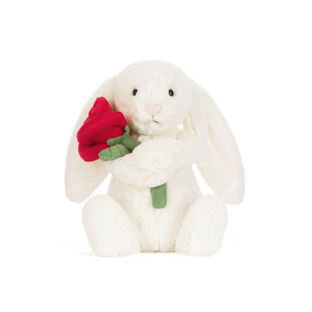 White plush bunny holding a red rose on a white background