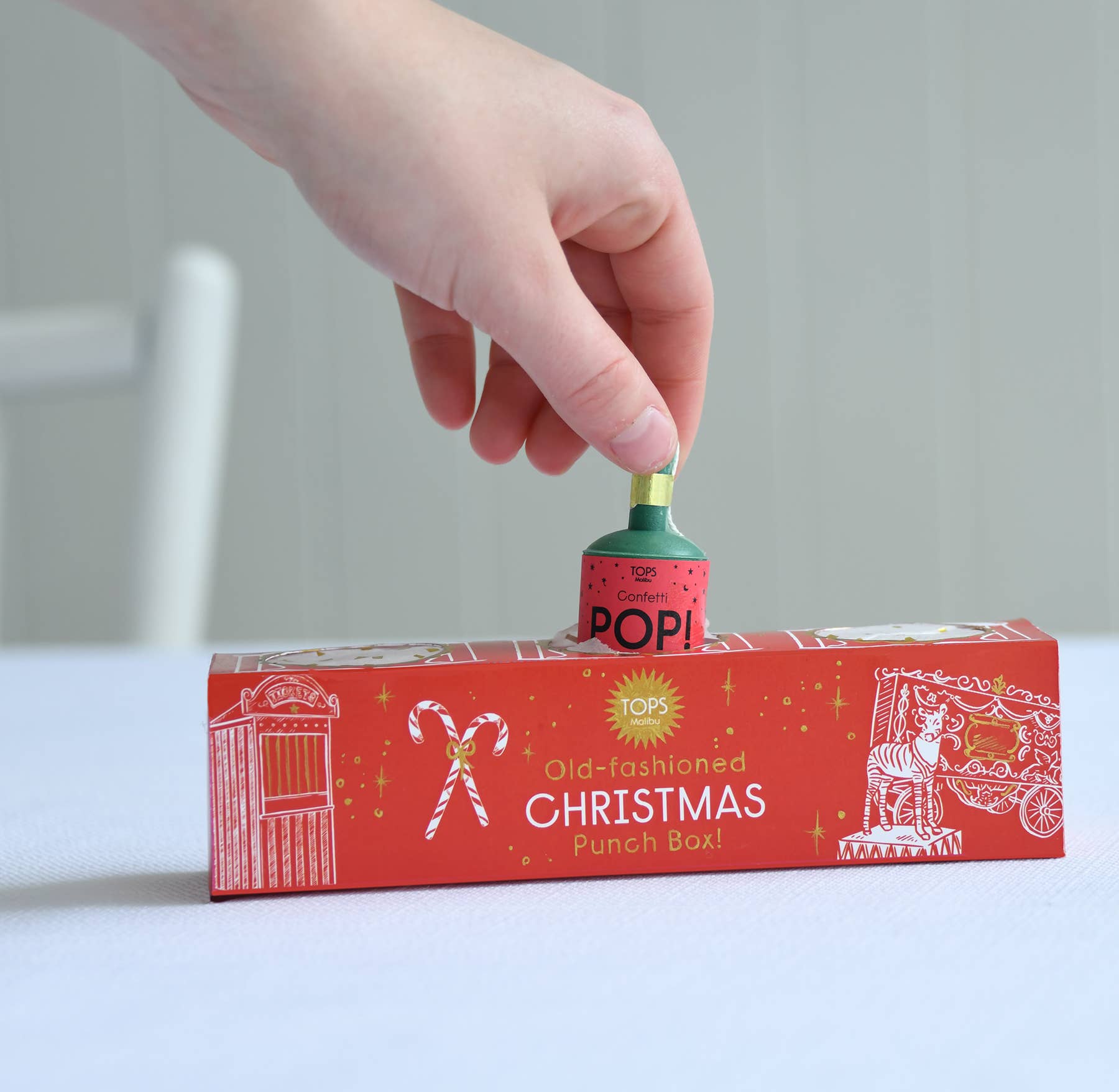 Hand inserting a small red and green container labeled 'POPI' into a red Christmas-themed punch box.
