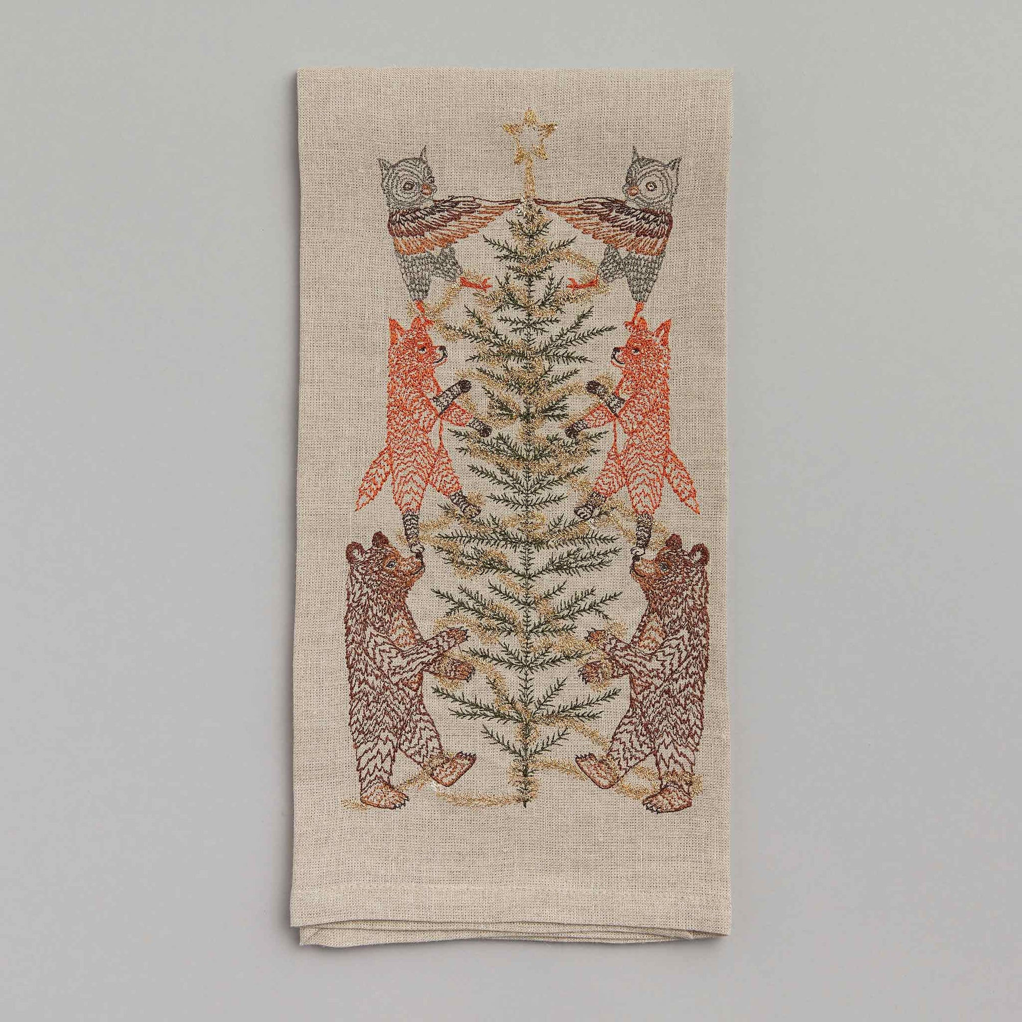 Decorative towel with embroidered design of bears around a Christmas tree on a gray background