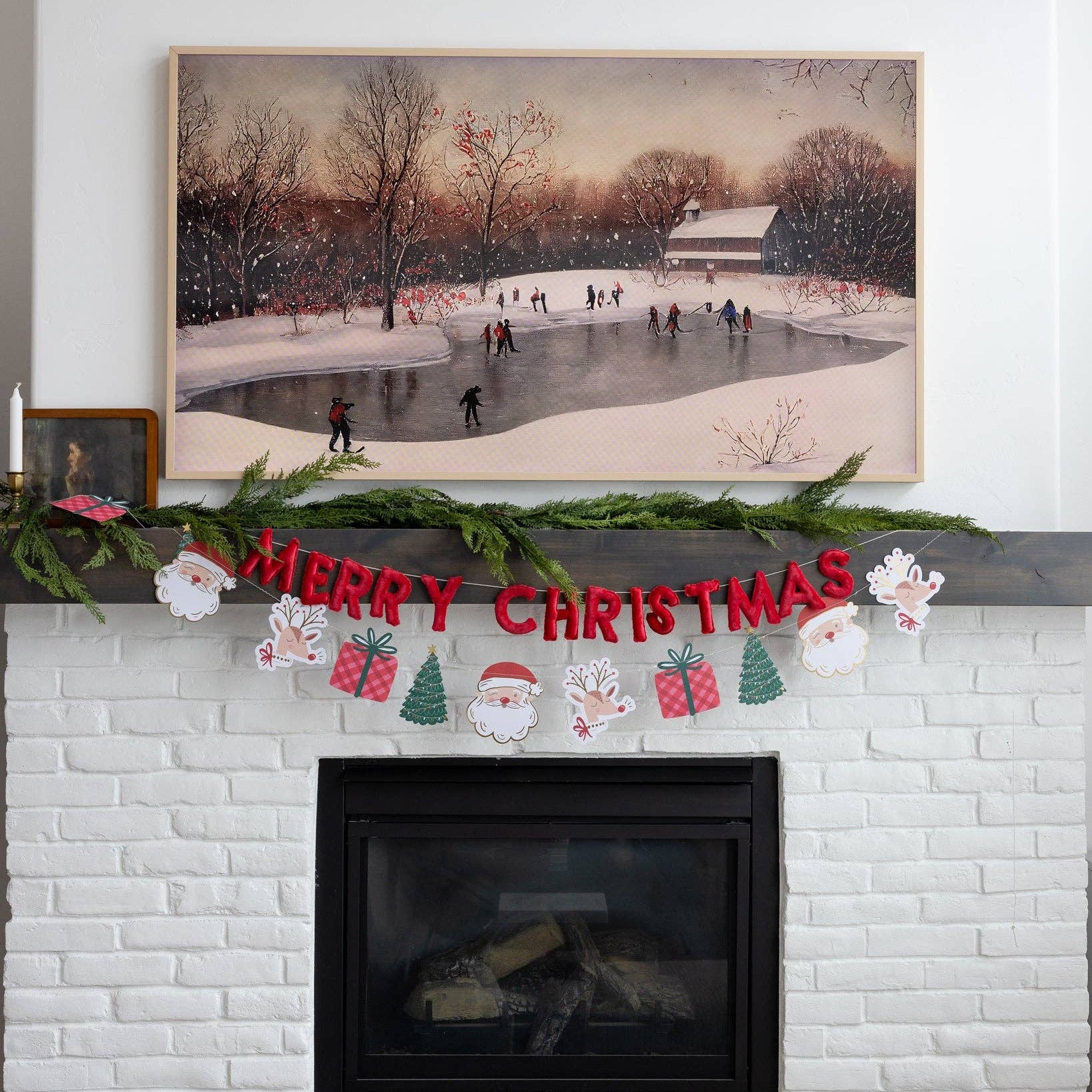Brick fireplace with Christmas decorations, including a 'Merry Christmas' sign and festive items, with a framed winter scene above.