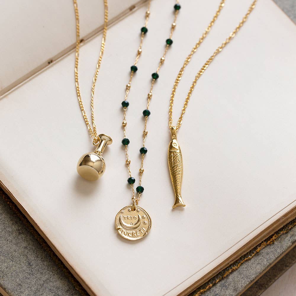 Three gold necklaces with various pendants on a white surface