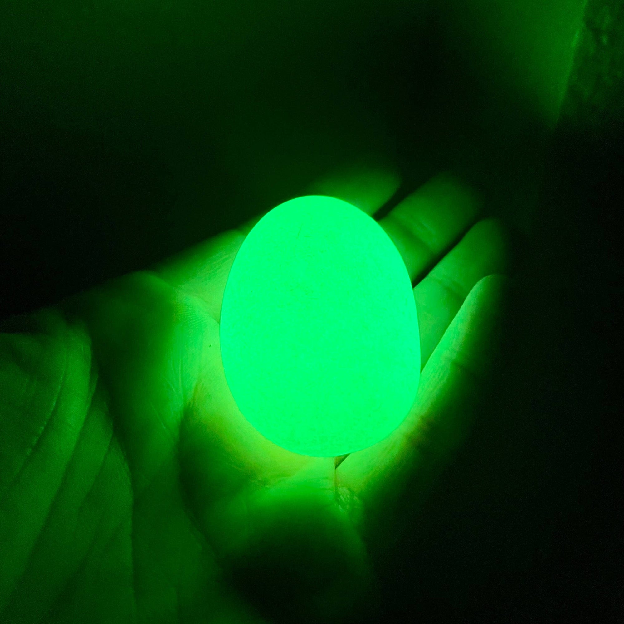 Hand holding a glowing green sphere against a dark background