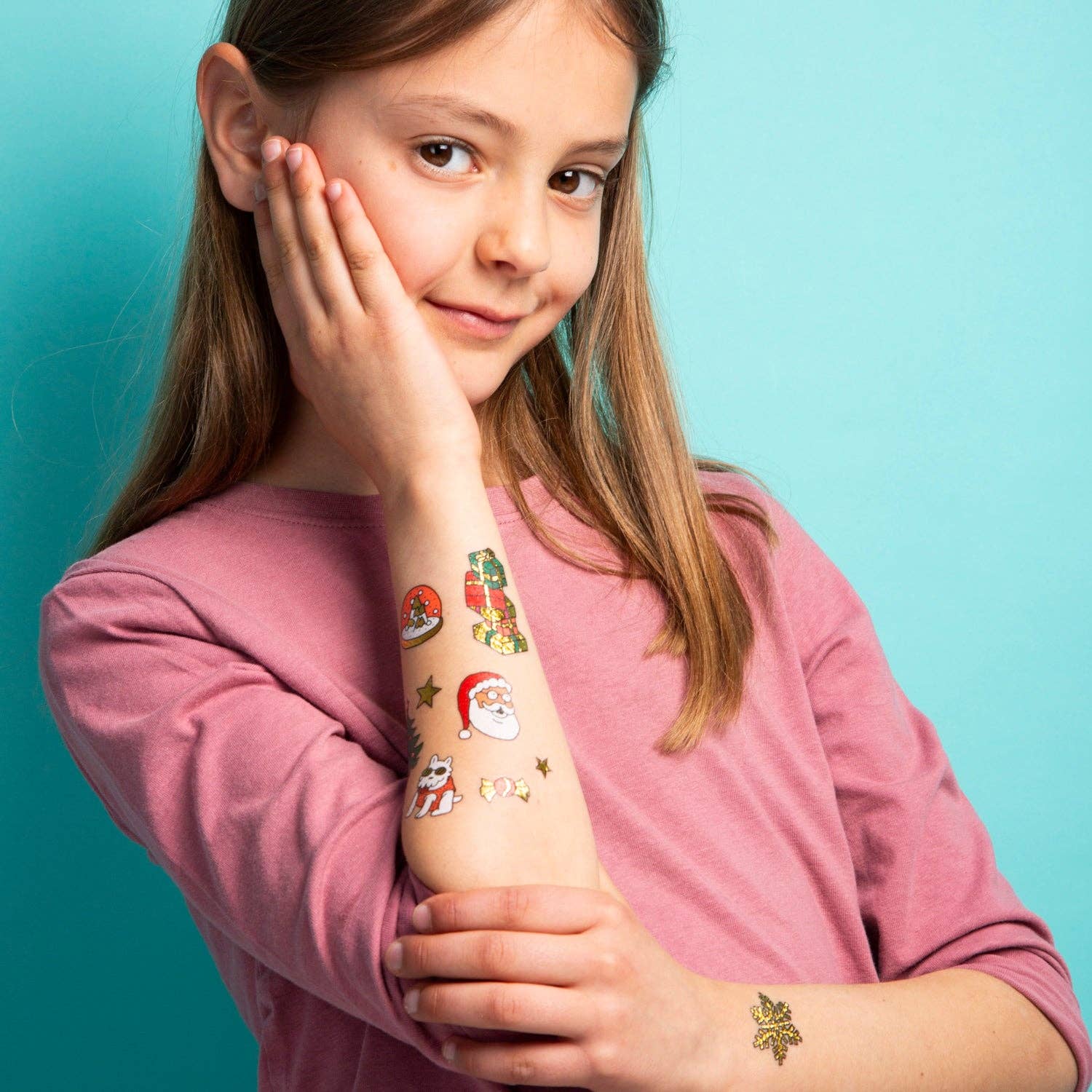 Young girl with temporary tattoos on her arm against a teal background