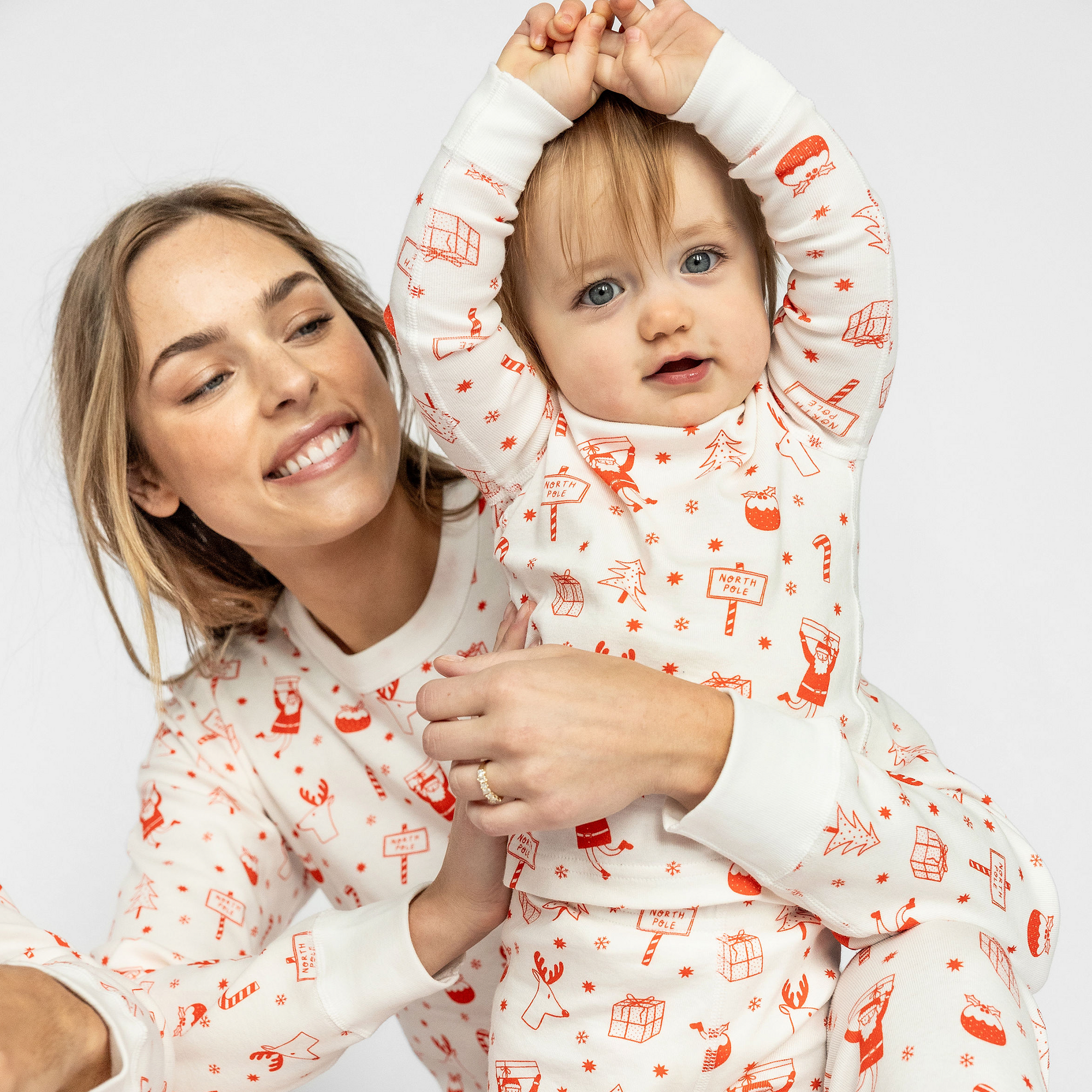 Woman and child wearing matching pajamas with red patterns on a white background