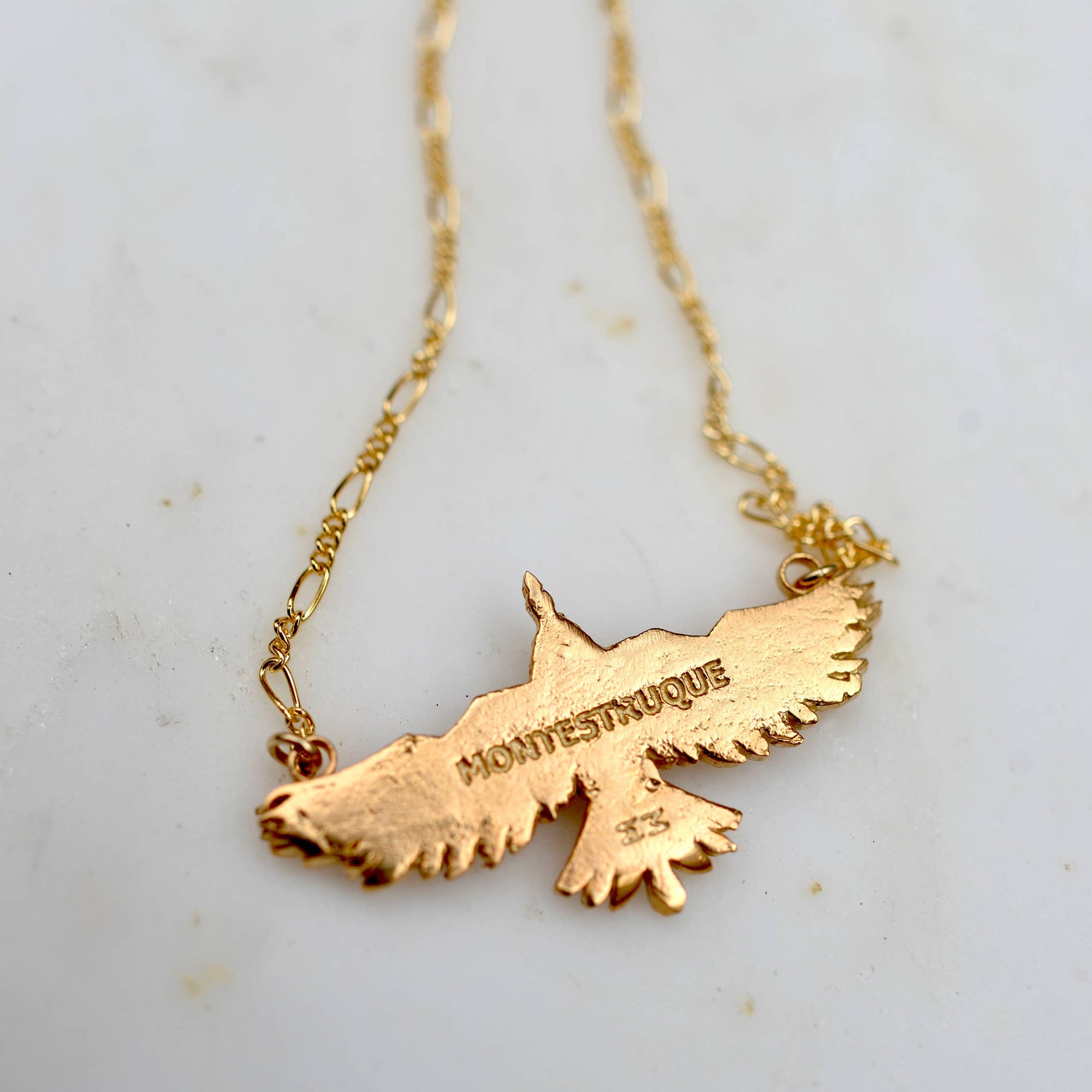Gold necklace with a map pendant on a light background