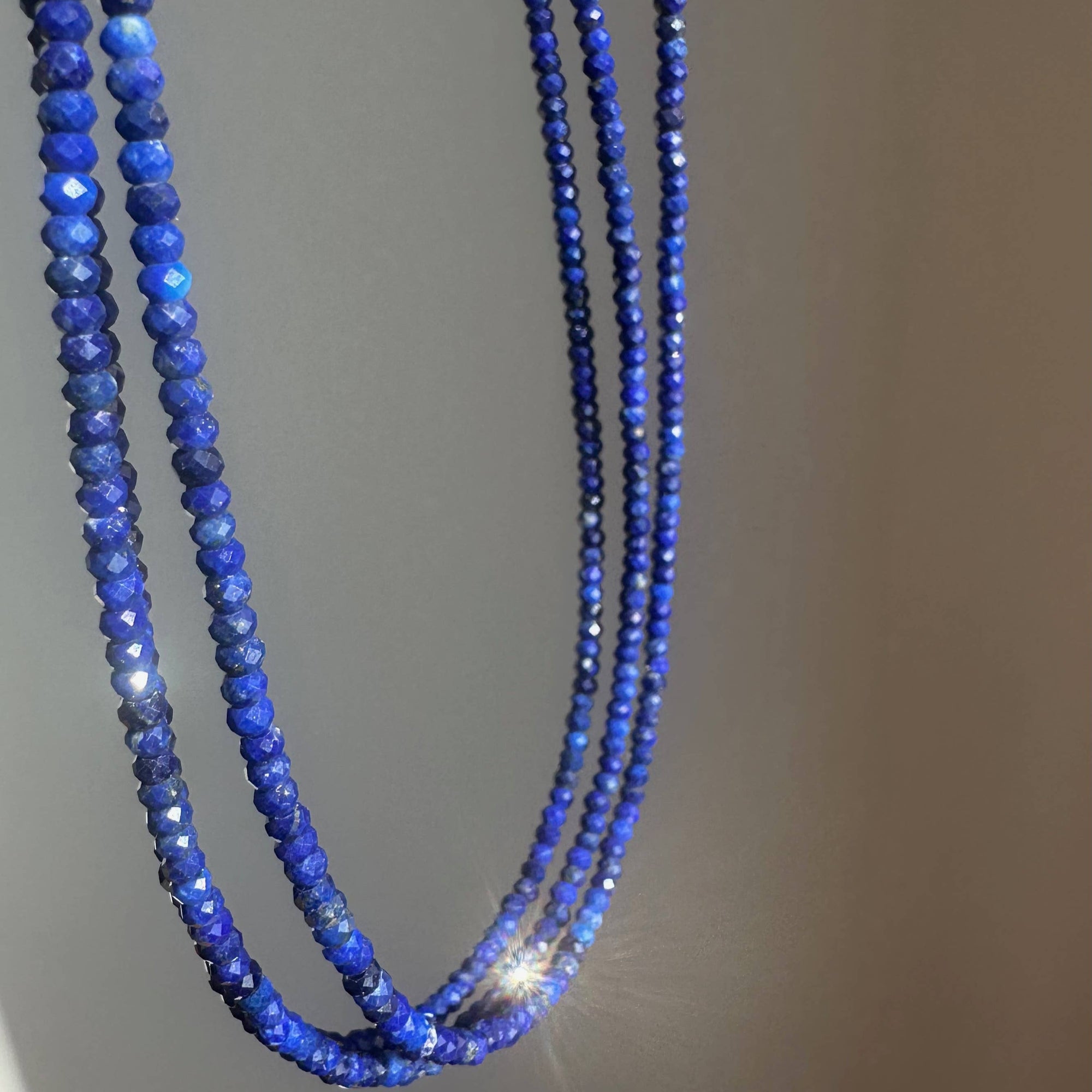Blue beaded necklace on a gray background